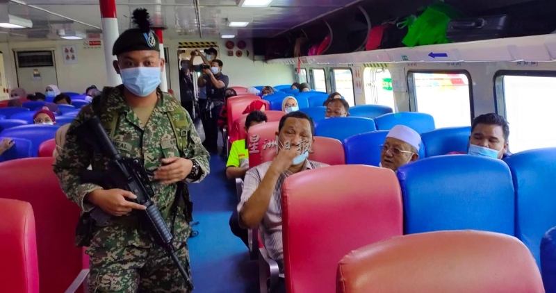 军人上船检查乘客的防疫措施，乘客受促戴好口罩。