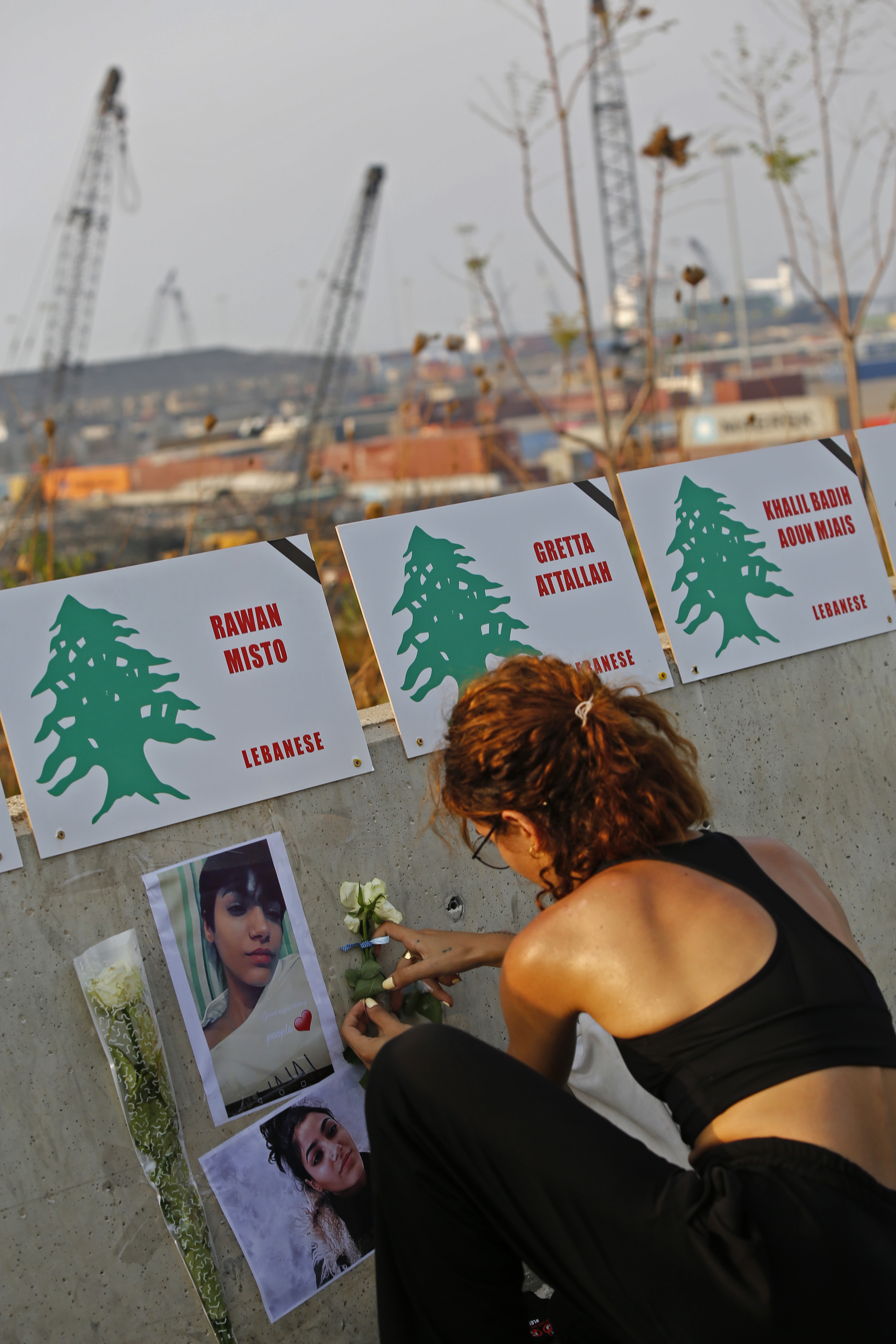 一名女子把遇难者照片和鲜花贴在路边，悼念逝世的亲友。（图：新华社）
