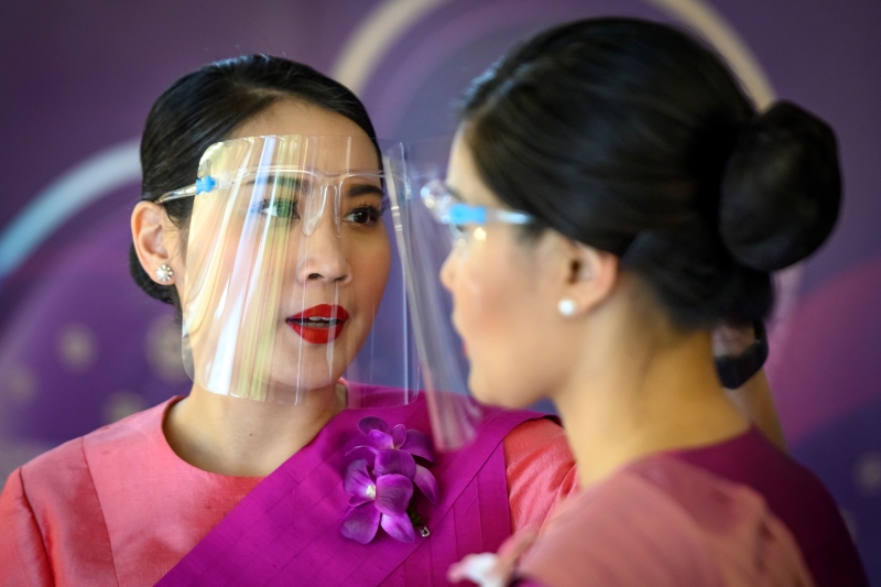 机组人员在曼谷航空公司总部的一家飞机主题餐厅里戴好防护面罩，准备投入服务。（法新社）