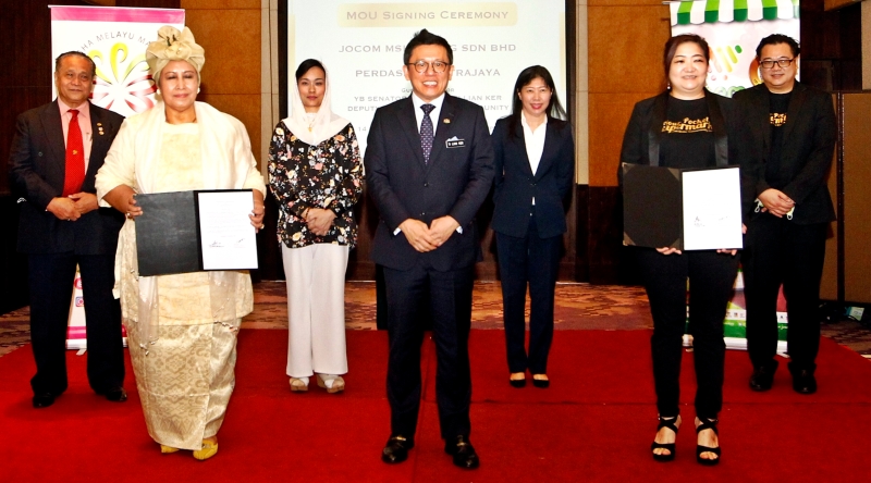 郑联科（中）见证Jocom董事经理蔡蕙冰（前排右）和马来人工商业协会代表罗哈娜签署备忘录。后右一为Jocom首席执行员萧文钦。