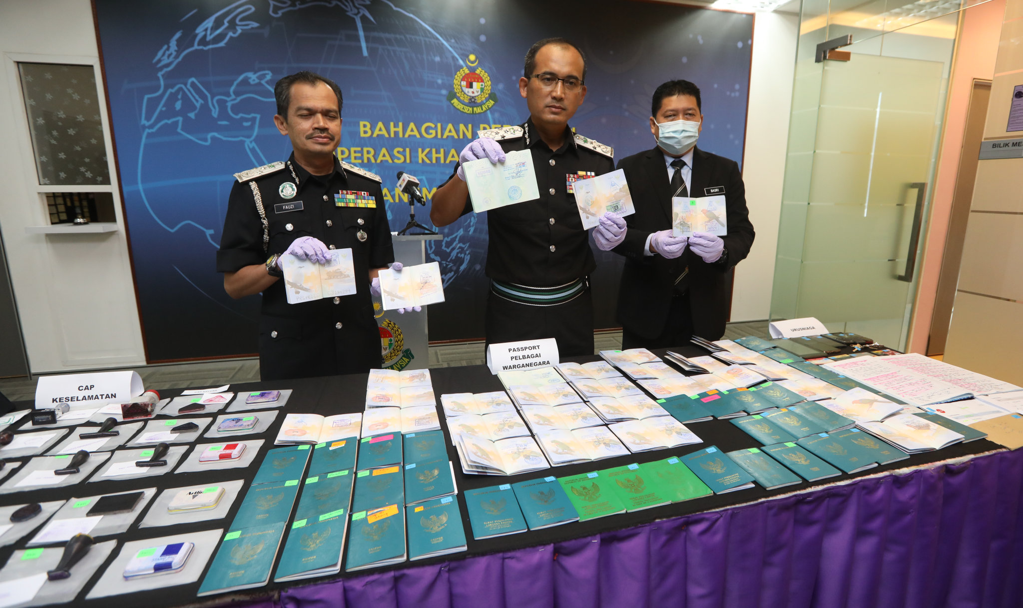 凯鲁（中）展示起获的印尼护照和伪造盖章。左为副总监法兹和右为情报、特别行动和分析组主任巴斯里。