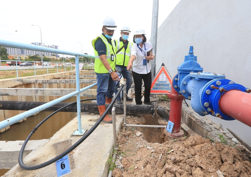 罗碧梅（右）及纳西尔（左）向媒体展示，本查阿南一间货仓从消防水管中取水，将水引入货仓内作为日常水供用途。