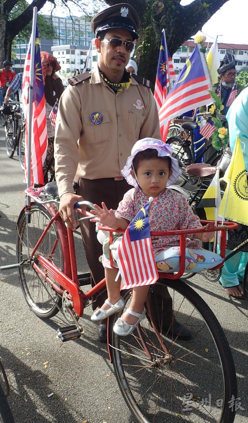 这名身穿旧时邮差制服的参加者，骑著载有小孩的邮差脚车。