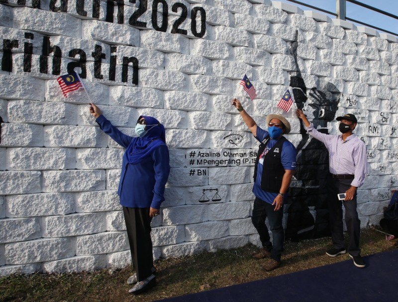 莎丽花（左起）、阿莎丽娜及赛西高举国旗，在壁画前模仿国父东姑阿都拉曼高喊“默迪卡”的手势拍照。