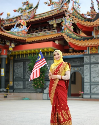 苏菲雅恩妮趁马来西亚日，特穿上纱丽，在西天宫九皇大帝庙挥舞国旗，她希望能借此传达大马多元文化特色，也展现各族团结融洽的意义。(摘自Sofea Erni脸书)
