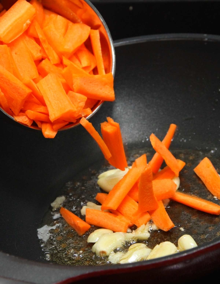热锅后爆香蒜头，加入少许盐，倒入切成条状的胡萝卜。