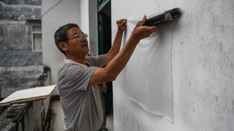 村民将制作好的贡川纱纸贴墙晾干。