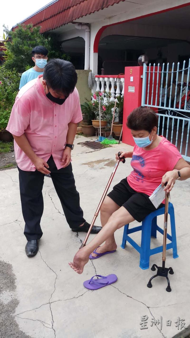 障友陈桂莲的脚因为浸在灾水中而发肿化脓。杨胜利在旁关心。