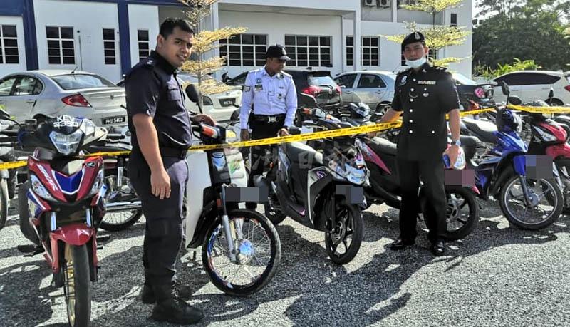 赛峇斯里（右一）与警官巡视被充公的摩托车。