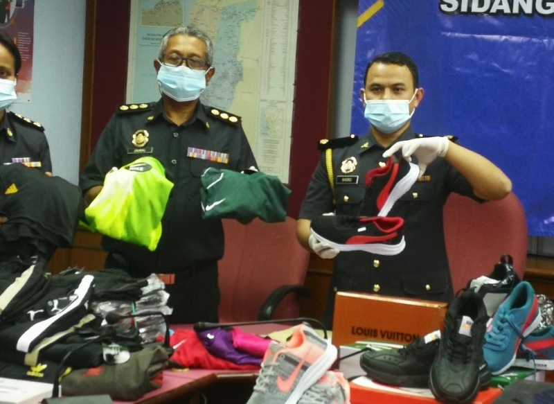 旺慕哈末峇德鲁）右）展示执法人员起获的疑似鹰制商品。