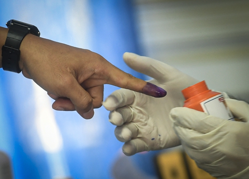 选委会工作人员为准备投票的警员手指上沾墨。
