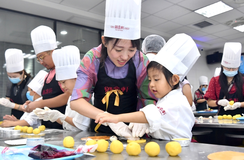 这位家长与孩子一起体验制作月饼的乐趣，促进亲子关系。
