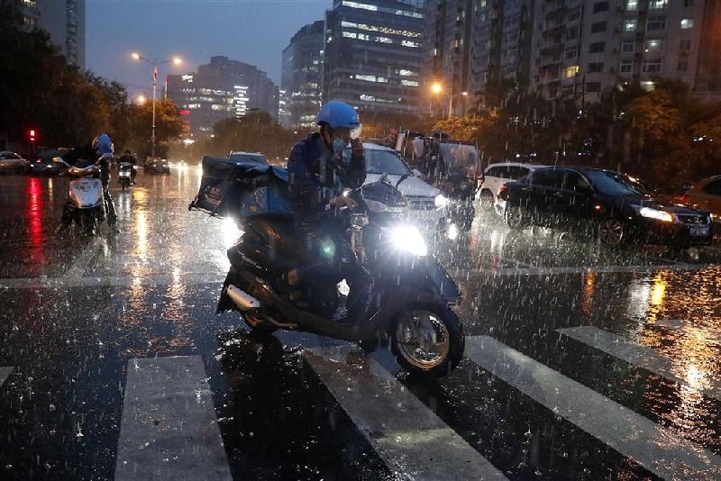 图为一名中国外送员在大雨中争分夺秒送餐，免得被扣钱。（图：中新社）