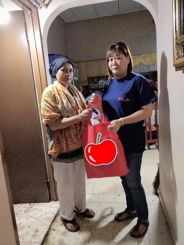 杨赞喜（右）代表州议员将装满乾粮和热饮的物资礼包送到灾民手上。