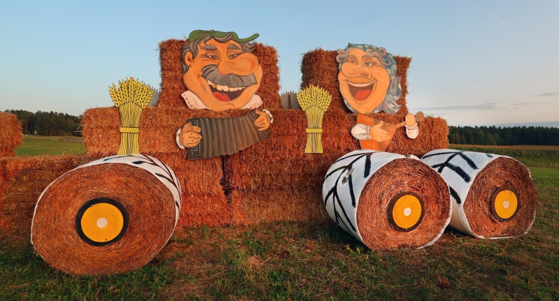 用乾草捆搭建的农机车上载着欢乐奏乐的农民肖像。