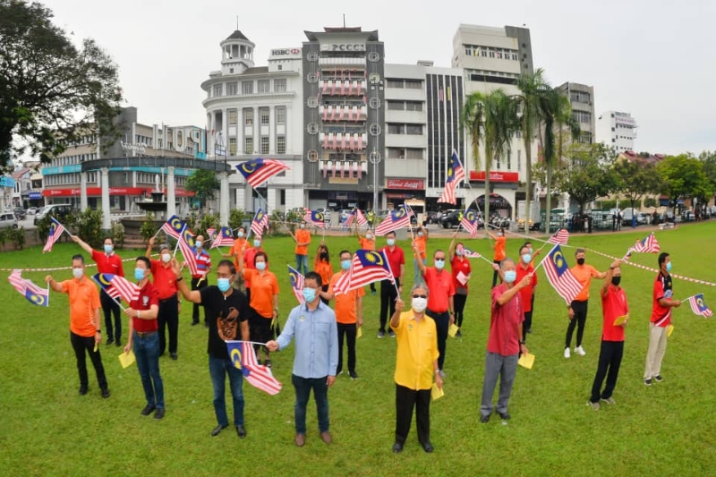 霹中总于大马日当天在怡保大草场举办“挥动辉煌条纹贺马来西亚日”庆典，出席的中央理事与会员及嘉宾挥动国旗唱起爱国歌曲。右三起是该会总会长拿督刘瑞裕、怡保市长拿督鲁迈兹和市议员邱文传，左二为刘宏杰。