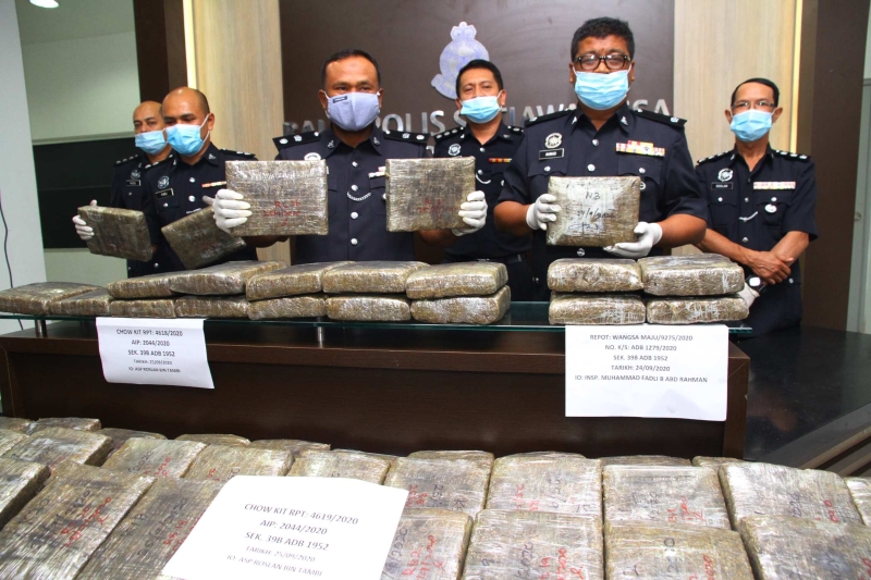 拉惹阿哈（右四）在其他警官陪同下召开新闻发布会，展示警方起获的大麻砖。