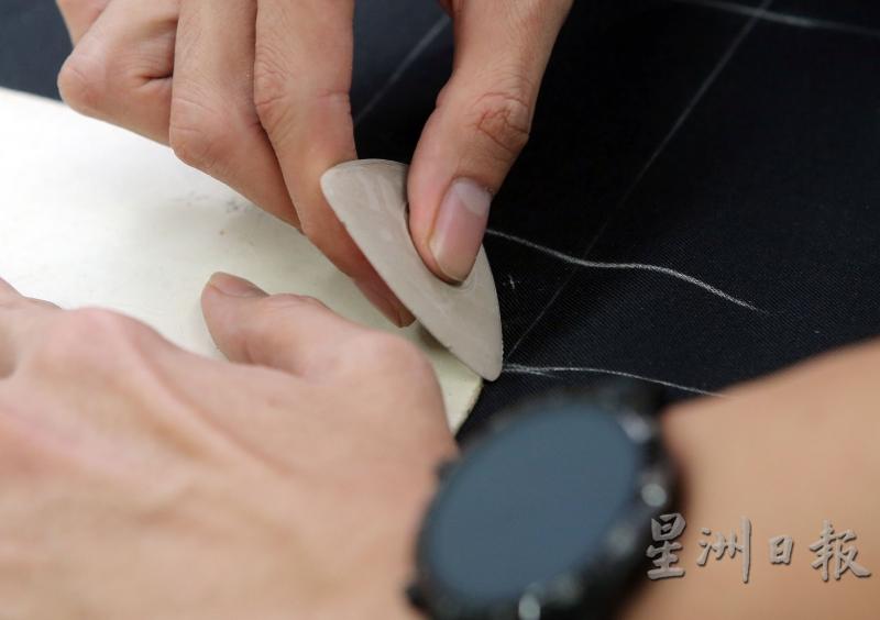 裁缝师根据纸样，在面料上勾勒出要裁剪的部分。