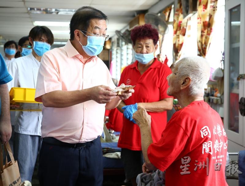 陈国伟（左）为同心乐龄关怀中心的孤老们，献上月饼及物资。

