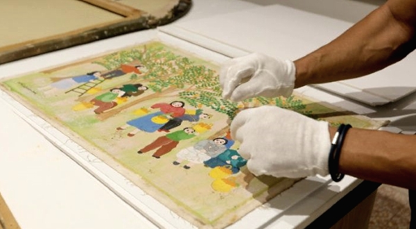 Artwork conservation specialist Gaby Maamary examines a damaged painting by late artist Sophie Yeramian. AFP