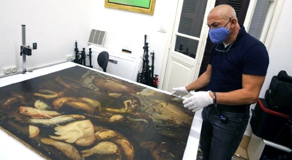 Artwork conservation specialist Gaby Maamary examines a 17th century painting by Italian painter Elena Recco, damaged in the Beirut port blast. AFP