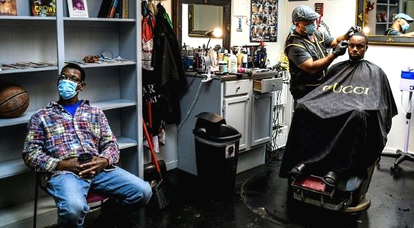 Antonio Wiggins (C) cuts the hair of James Bennett as Robert White waits for his turn in Jackson, Mississippi. AFP