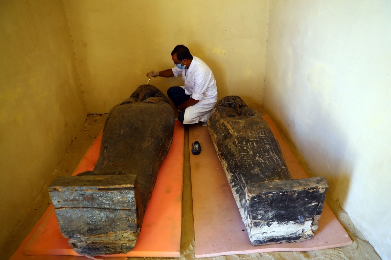 工作人员在埃及吉萨省塞加拉地区的考古现场处理出土的木棺。