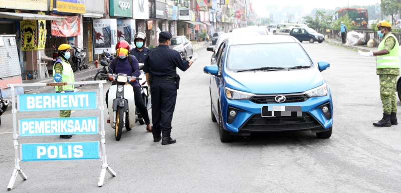 军警在设立路障区进行排查，仔细地调查司机身份和去向。