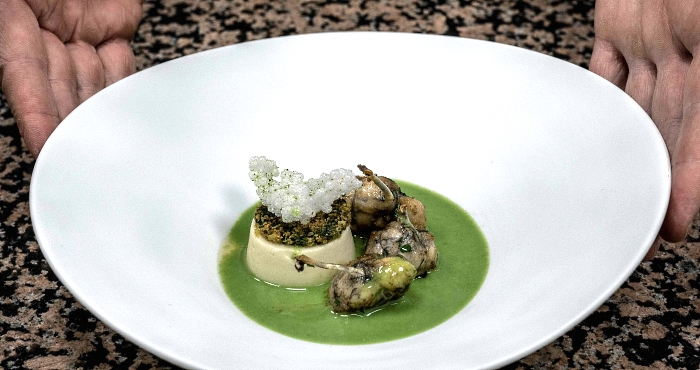 French chef Gilles Reinhardt shows a plate with frog legs in Paul Bocuse's restaurant 