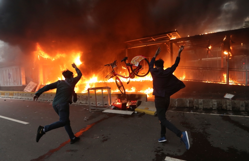 雅加达示威者周四纵火烧车站。（美联社照片）