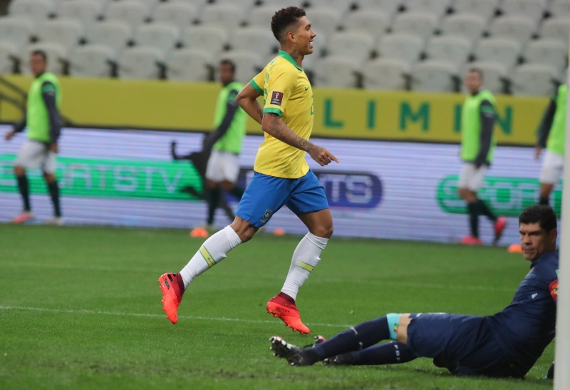 菲尔米诺（左）打进巴西本场比赛的第3球后，扬长而去庆祝，留下跌坐草场上的玻利维亚门将兰佩无奈的看着皮球入网 。（美联社照片）