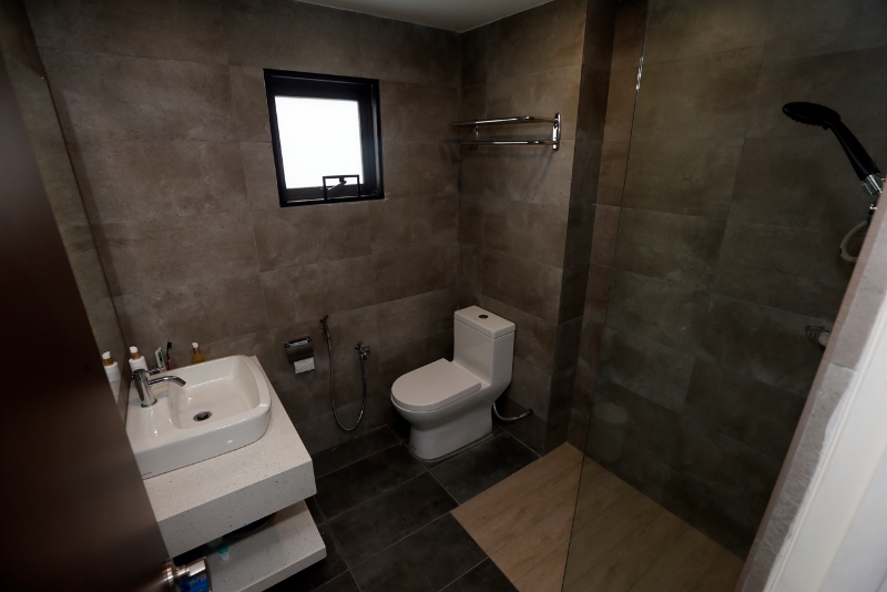 虽然浴室空间不大，但以深色系打造，并设有挡水玻璃，简约式的现代化的风格。