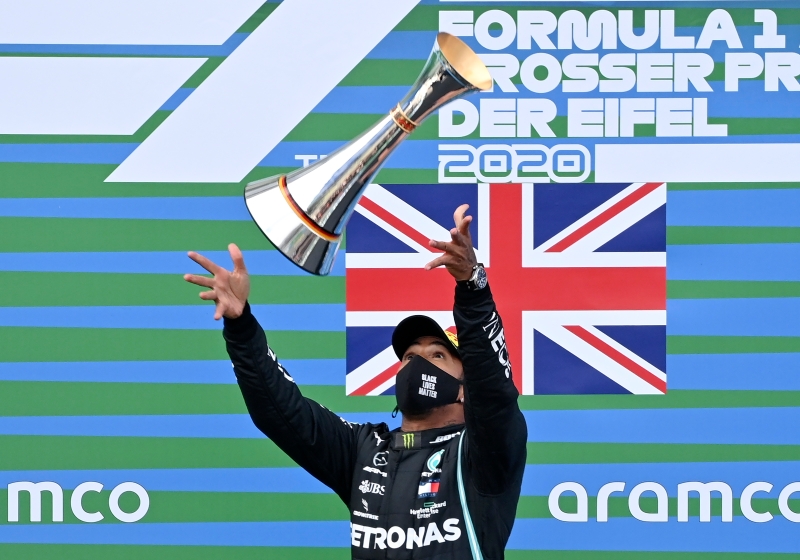 汉密尔顿在德国艾菲尔站F1大赛车拿下了生涯第91个分站冠军，追平了德国“车神”舒马克的历史分站夺冠纪录，让他在领奖台幸福得将奖杯高高抛起庆祝。（欧新社照片）