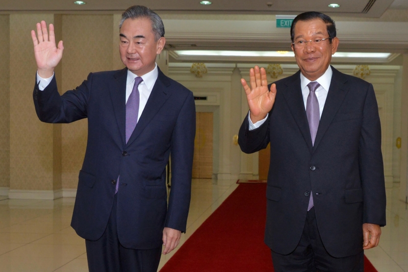 柬埔寨总理洪森（右）与中国外长王毅在柬埔寨总理府和平大厦举行会晤期间，向众人挥手示意。（法新社照片）