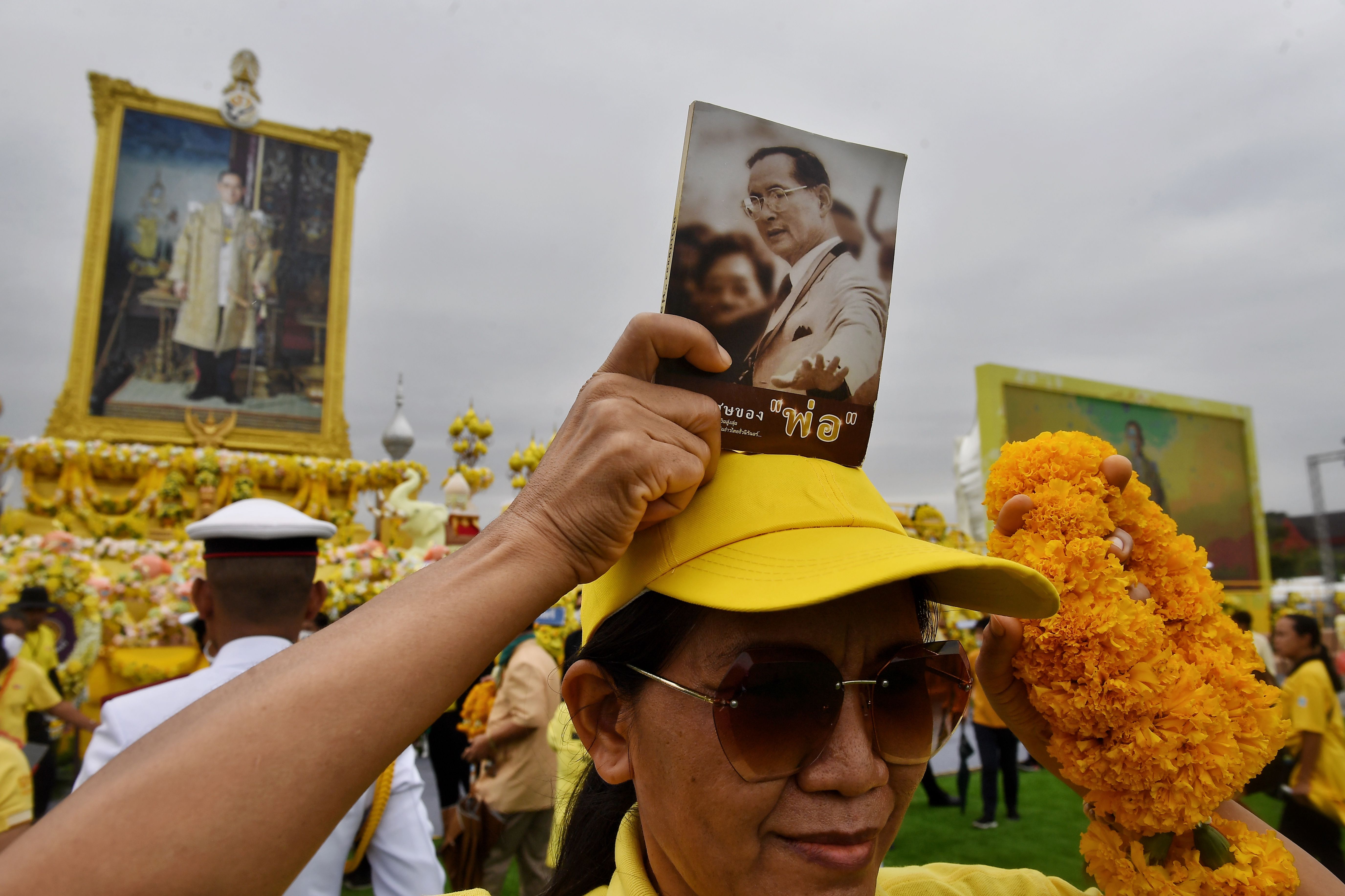 泰国民众手持九世王的照片，到大王宫出席大型悼念仪式。