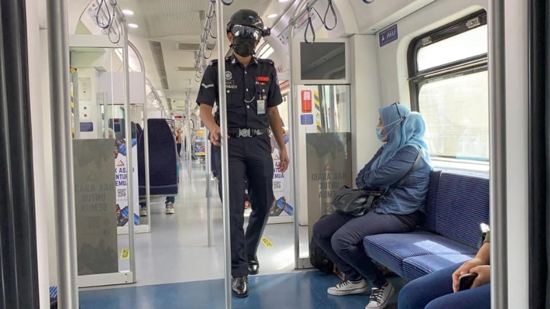 辅警戴上体温测量头盔在火车站及列车内进行巡逻。