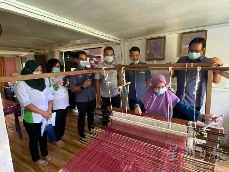 砂农业、土著地及区域发展部助理部长阿都拉曼依斯迈（右）观看玛斯妮（坐者）纺织宋吉锦。