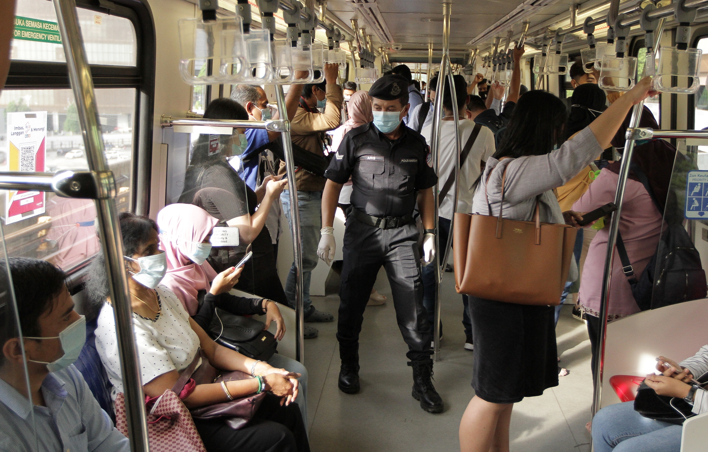 辅警巡视轻快铁车厢，确保大家都有佩戴口罩。