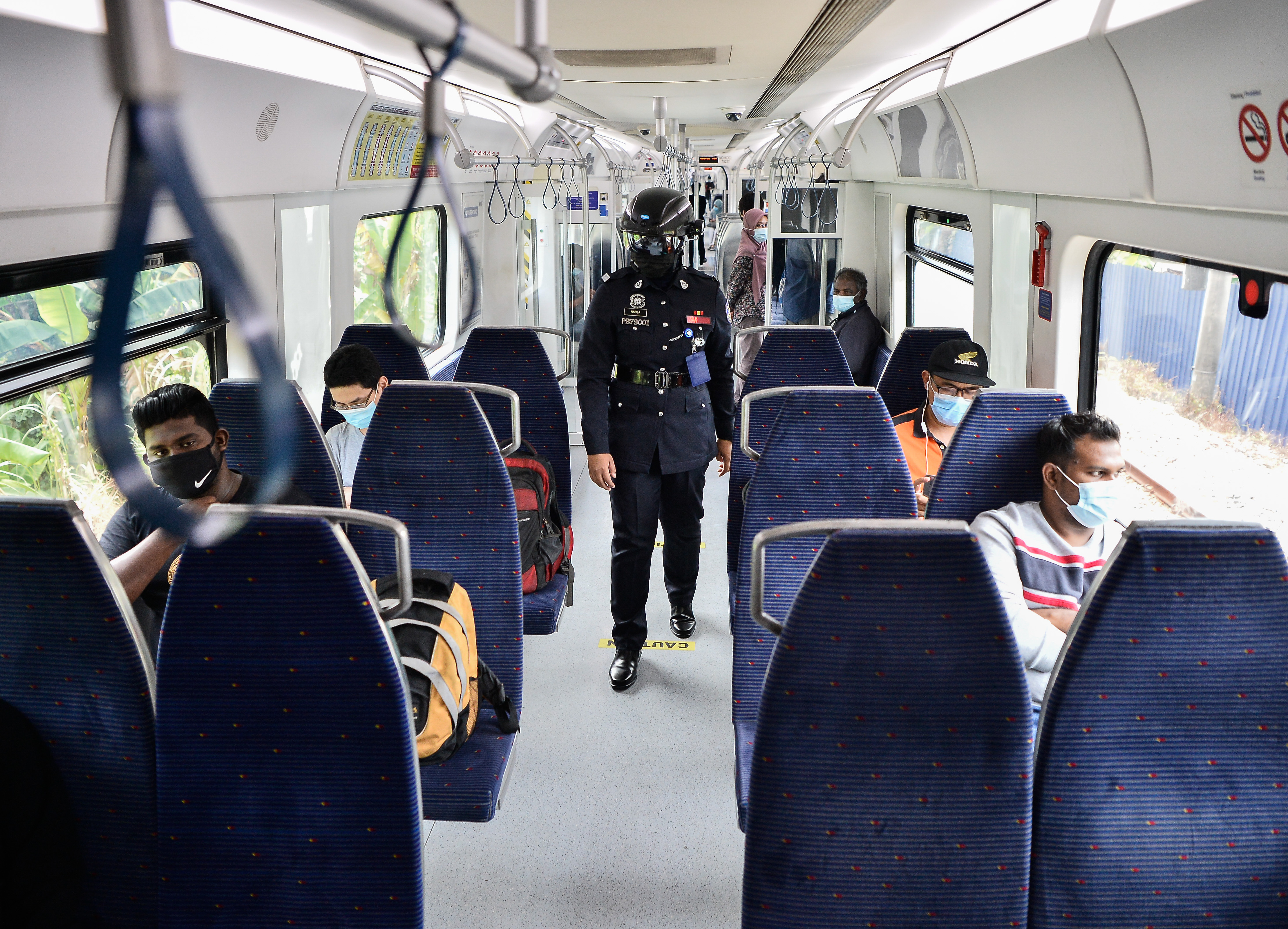 戴上体温测量头盔的辅警在电动火车车厢巡视。