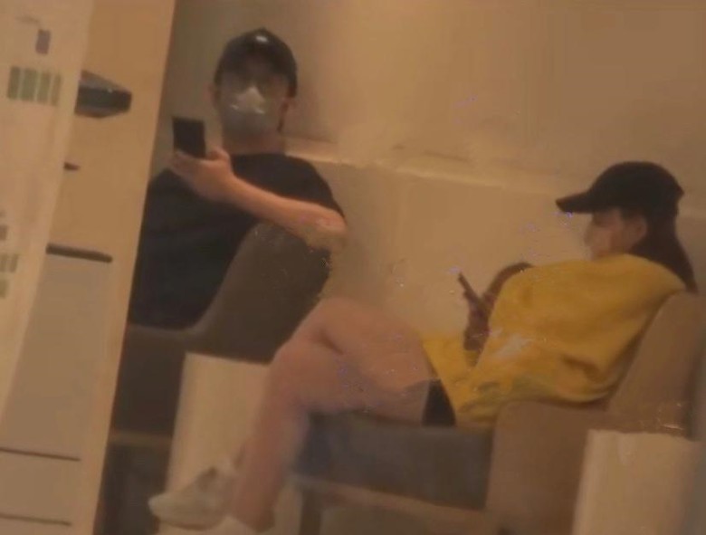 李治廷女友穿黄色卫衣配短裤，穿着十分宽松，进医院后一边玩手机一边等待检查。

