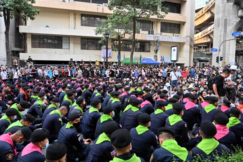 示威者举行集会，防暴警察则坐在地上。