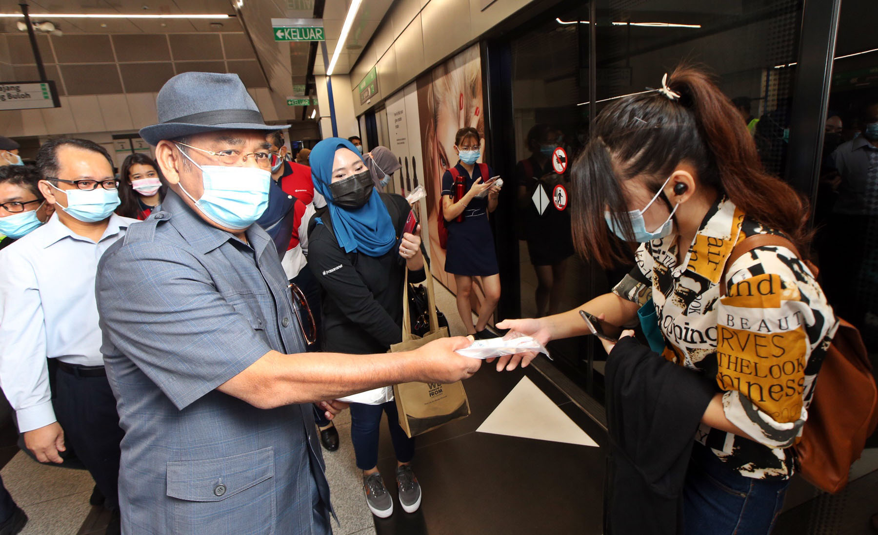 达祖丁（左）在捷运站派送口罩给乘客。