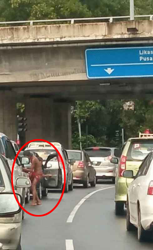 半裸男在马路上向路过司机讨钱。
