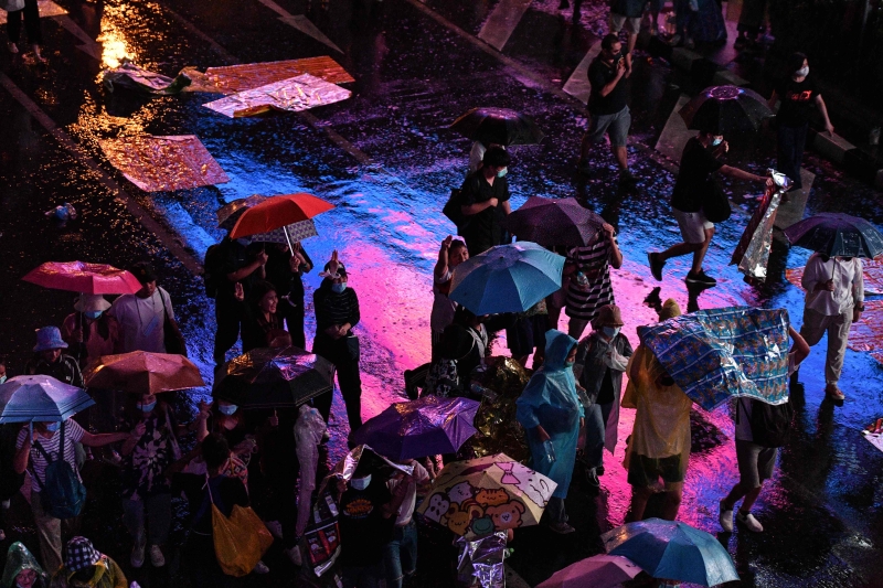 泰国当局出动水炮车，一些示威者以雨伞和塑胶袋作为遮掩。（图：法新社）