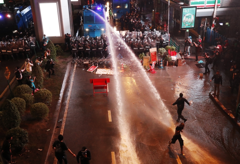 防暴警察身后的水炮车射出两条水柱，驱散聚集在路上的示威者。（图：欧新社）