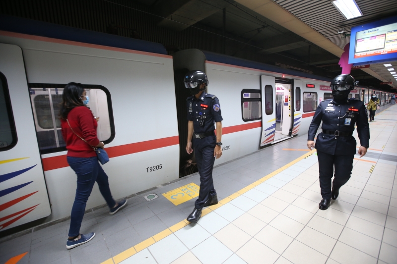 辅警戴上体温测量头盔在火车站台上进行巡逻。