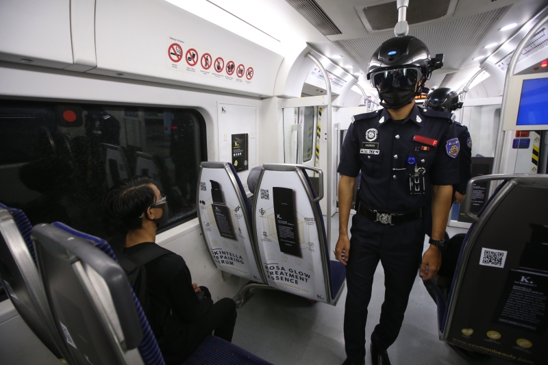 戴上体温测量头盔的辅警除了在火车月台上巡逻，也进入车厢内进行检查。