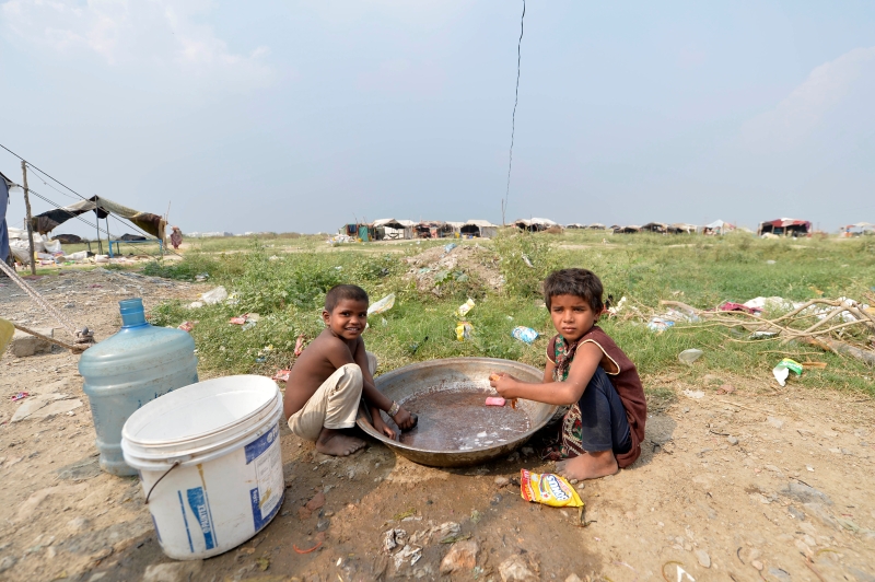 在巴基斯坦拉瓦尔品第的一处贫民窟，儿童在帐篷外戏水玩耍。(新华社照片)