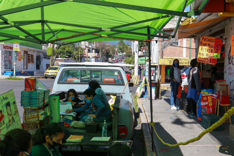 在墨西哥首都墨西哥城，学生们在路边的皮卡车上温习功课。 (新华社照片)