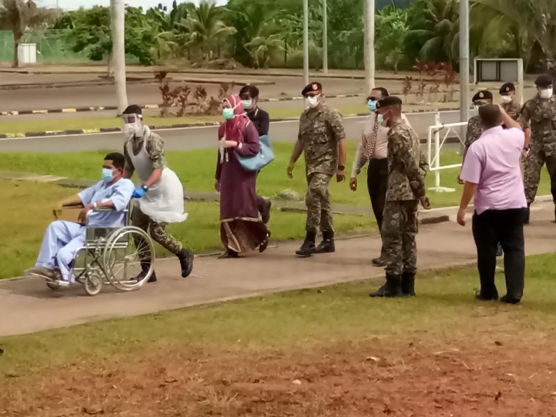 坐轮椅的首名病患（前）在贵宾陪伴下进入战地医院。